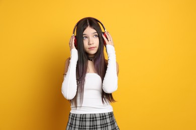 Photo of Teenage girl wearing stylish clothes and accessories on orange background. Makeup in anime style