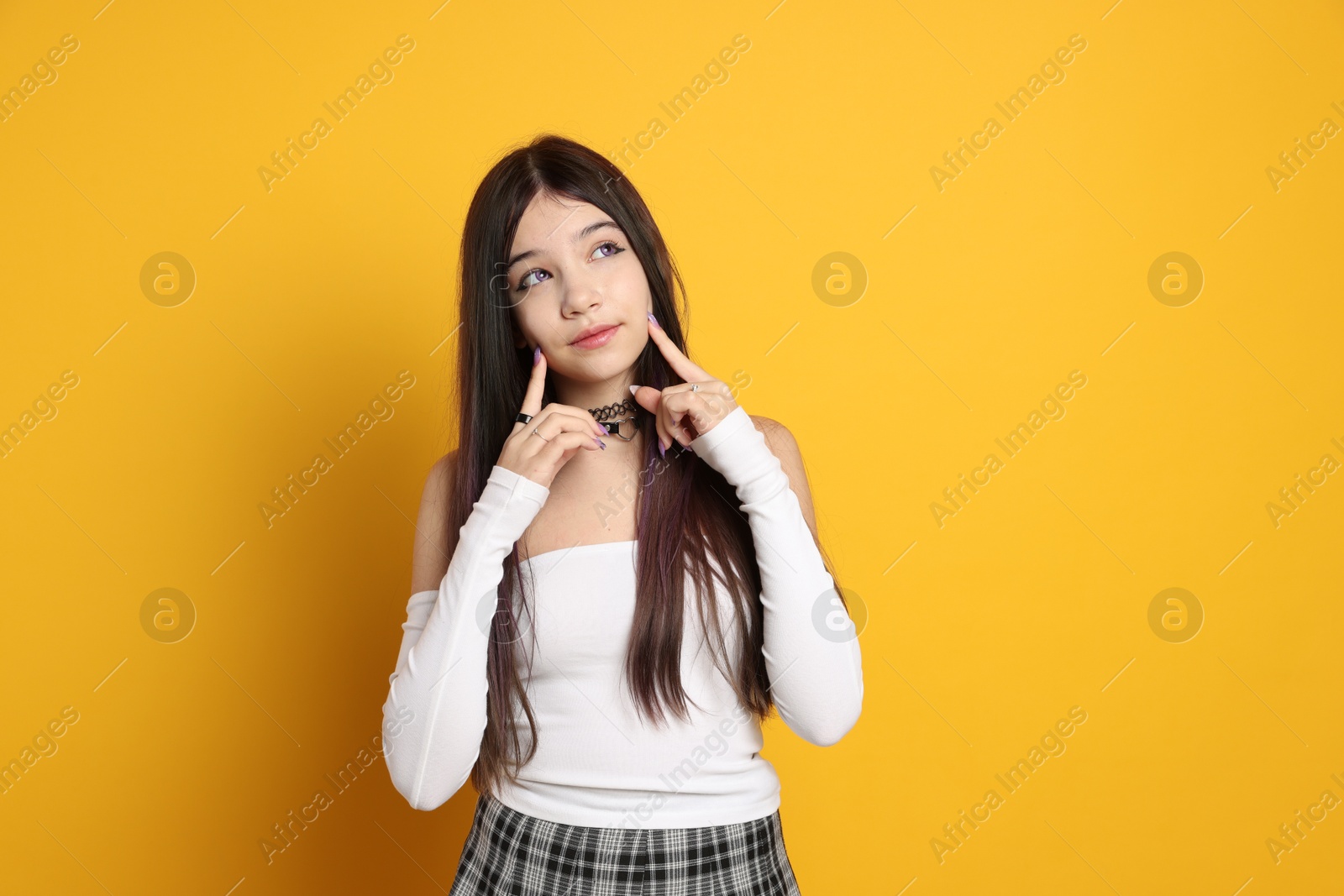 Photo of Teenage girl wearing stylish clothes and accessories on orange background. Makeup in anime style