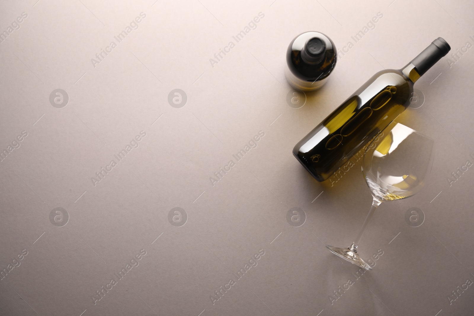 Bottles of wine and glass on light grey background, flat lay. Space for text Photo of Bottles of wine and glass on light grey background, flat lay. Space for text