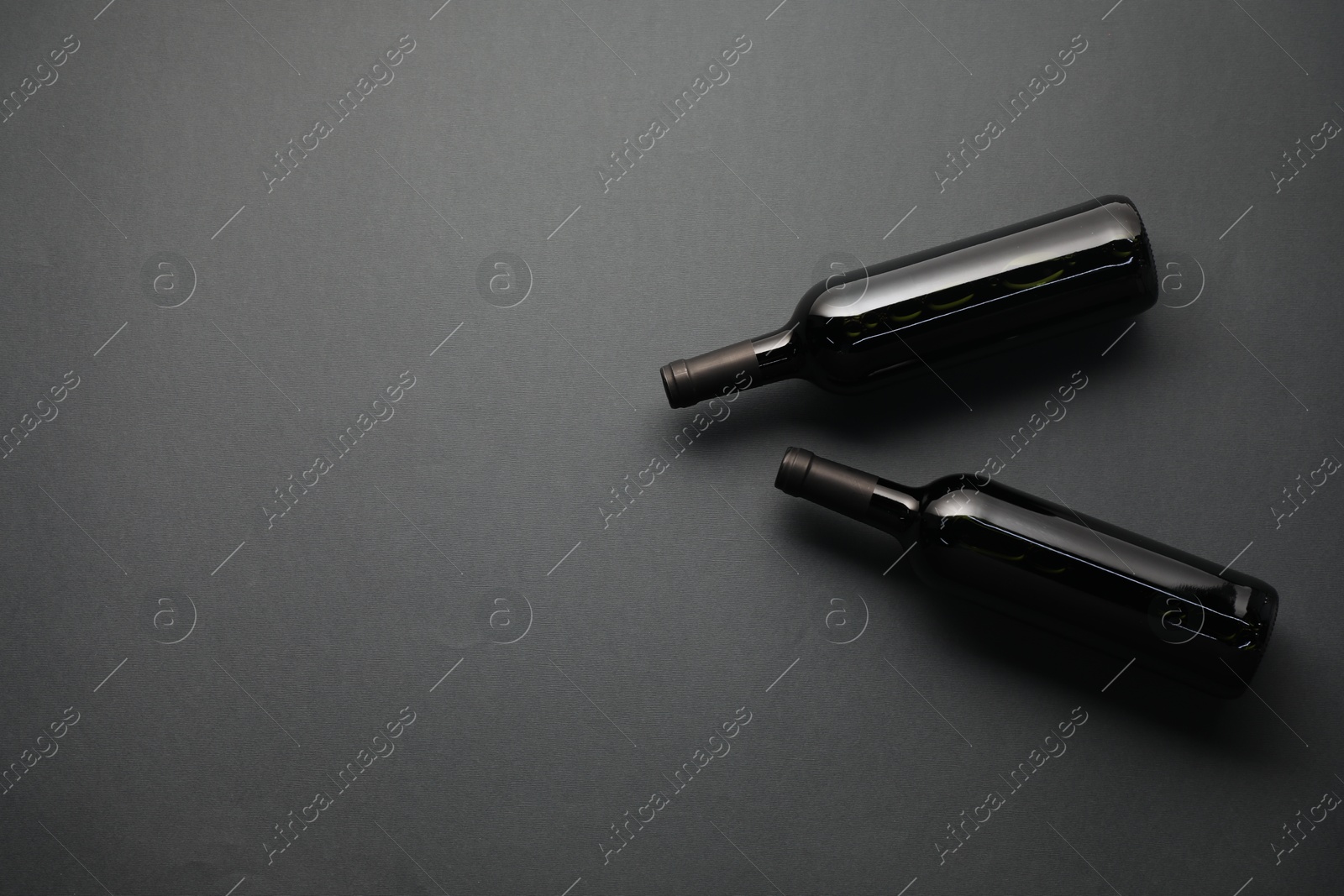 Bottles of wine on grey background, flat lay. Space for text Photo of Bottles of wine on grey background, flat lay. Space for text