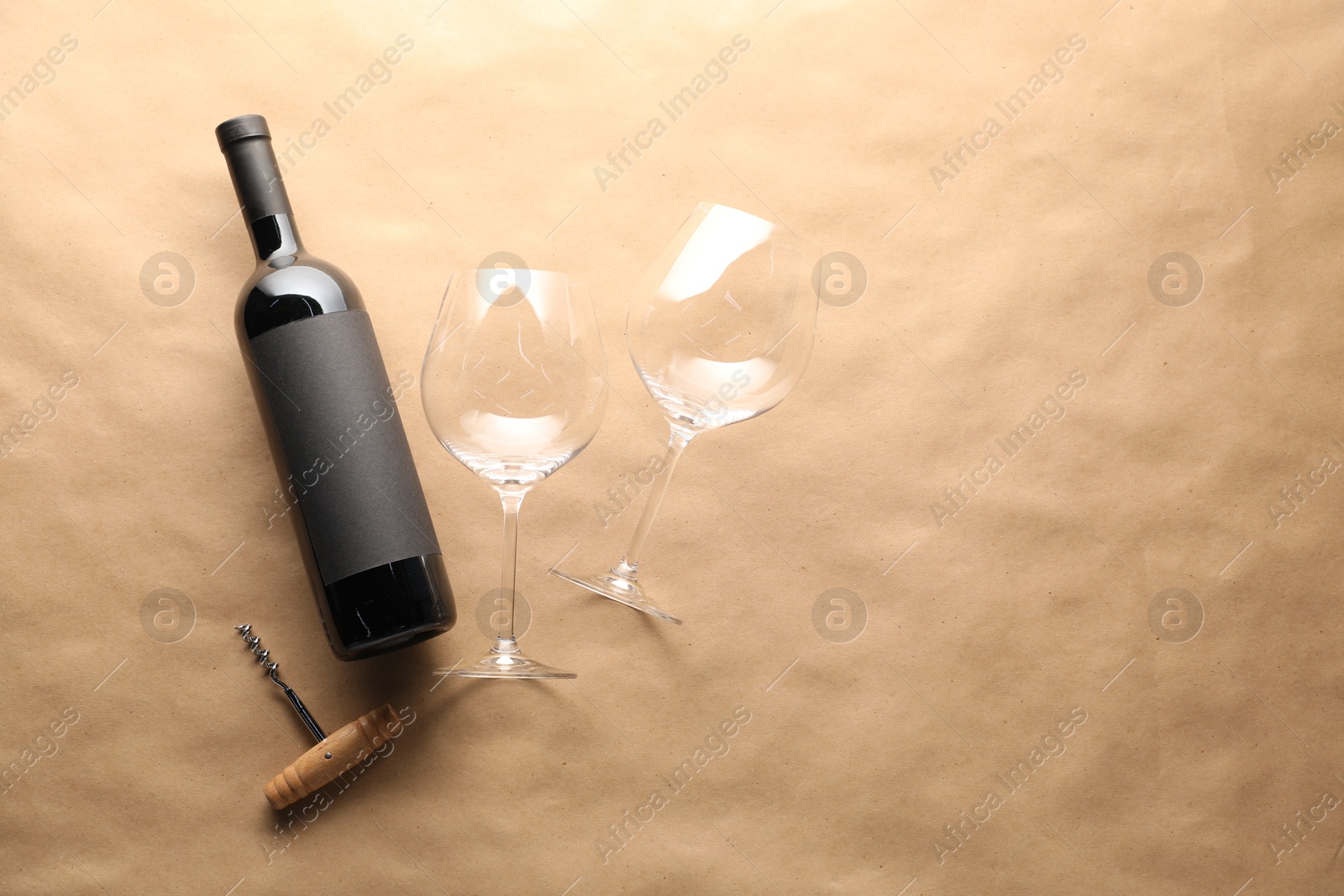 Bottle of wine, glasses and corkscrew on parchment paper, flat lay. Space for text Photo of Bottle of wine, glasses and corkscrew on parchment paper, flat lay. Space for text
