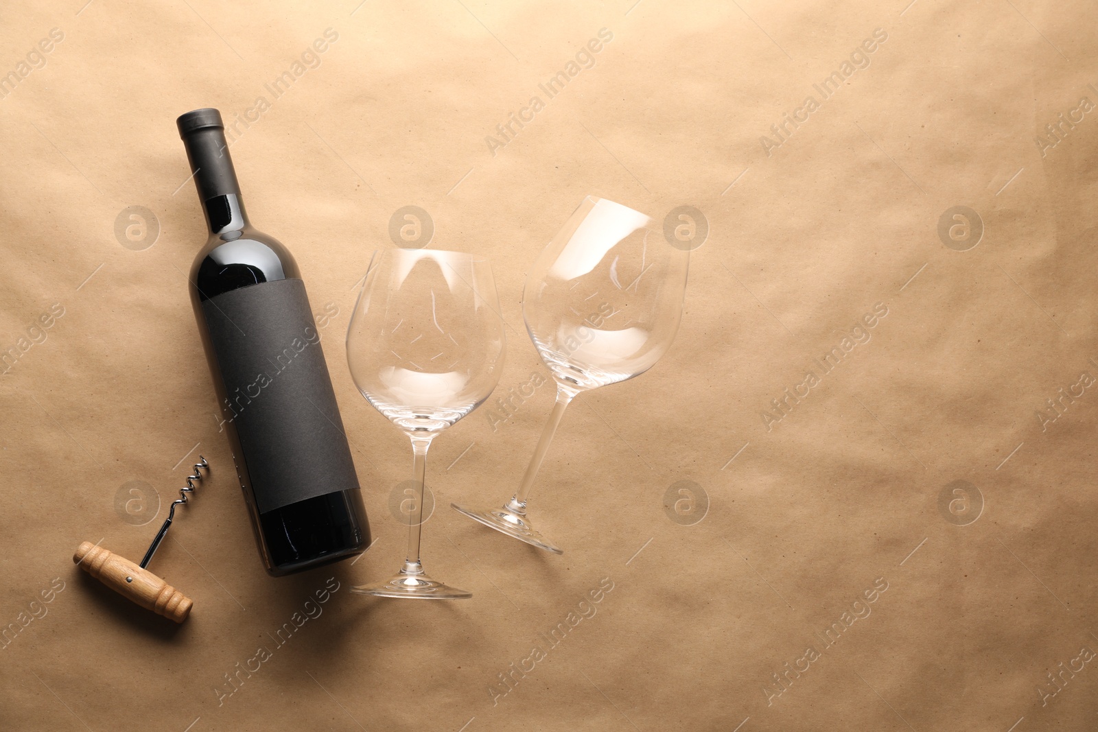 Bottle of wine, glasses and corkscrew on parchment paper, flat lay. Space for text Photo of Bottle of wine, glasses and corkscrew on parchment paper, flat lay. Space for text