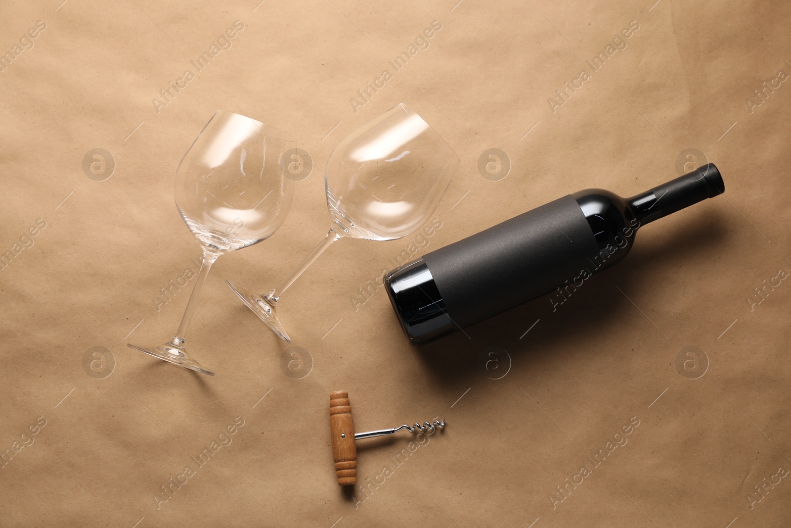 Bottle of wine, glasses and corkscrew on parchment paper, flat lay Photo of Bottle of wine, glasses and corkscrew on parchment paper, flat lay