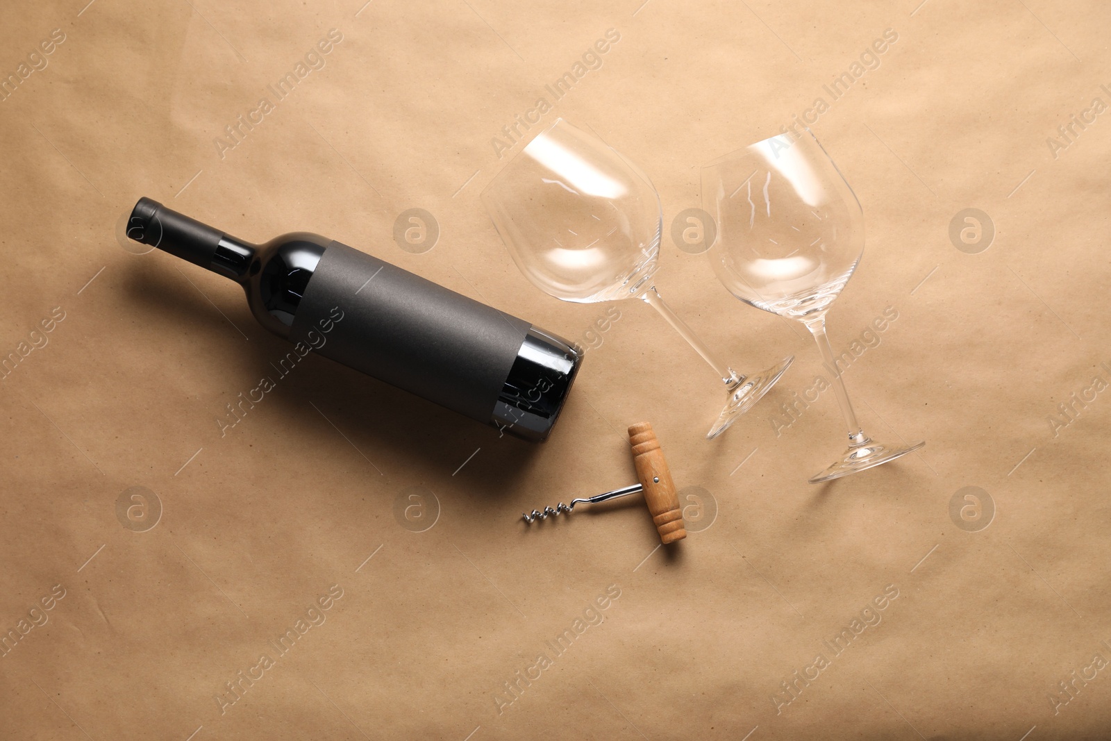 Bottle of wine, glasses and corkscrew on parchment paper, flat lay Photo of Bottle of wine, glasses and corkscrew on parchment paper, flat lay