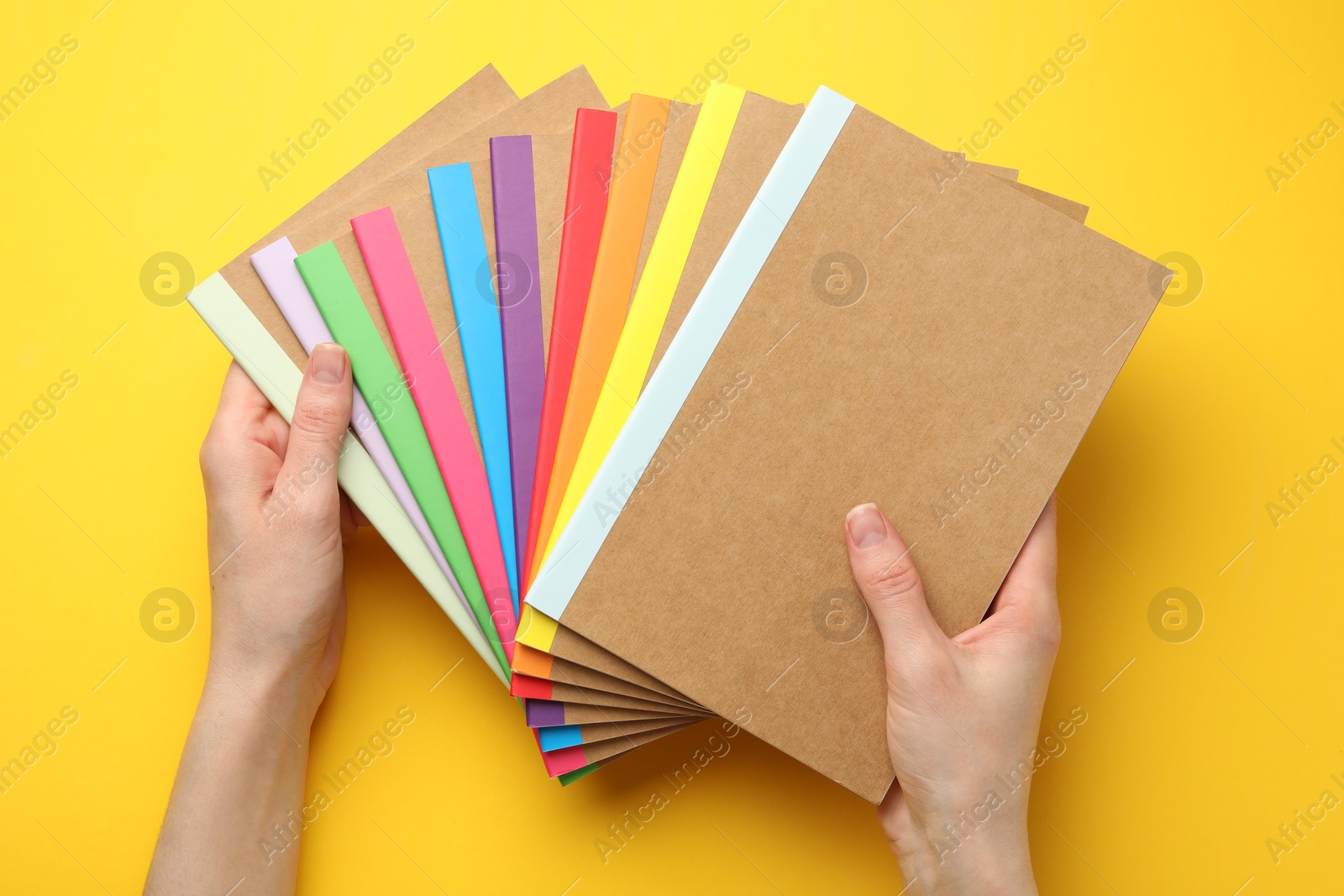 Photo of Woman with different copybooks on yellow background, top view