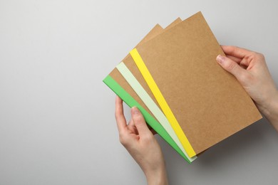 Photo of Woman with different copybooks on light grey background, top view. Space for text