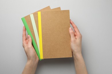 Photo of Woman with different copybooks on light grey background, top view