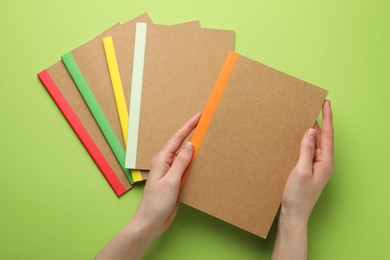 Photo of Woman with different copybooks on green background, top view