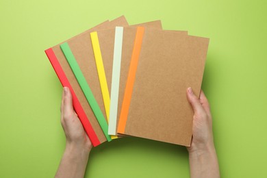 Photo of Woman with different copybooks on green background, top view