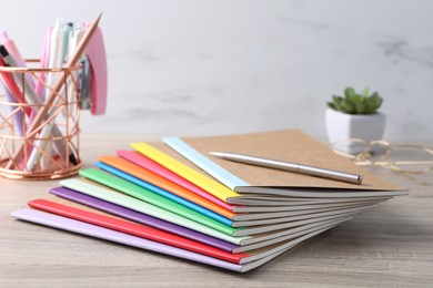 Photo of Different copybooks and other stationery on wooden table, closeup