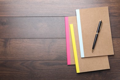 Photo of Different copybooks and pen on wooden table, top view. Space for text