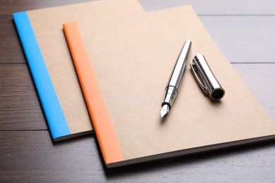 Photo of Copybooks and fountain pen on wooden table, closeup