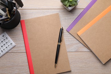 Photo of Copybooks and other different stationery on wooden table, flat lay