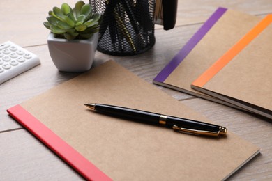 Photo of Copybooks and other different stationery on wooden table, closeup