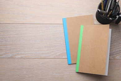 Photo of Copybooks and other different stationery on wooden table, flat lay. Space for text