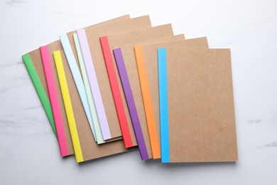 Photo of Different copybooks on white marble table, flat lay