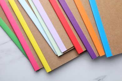 Photo of Different copybooks on white marble table, flat lay