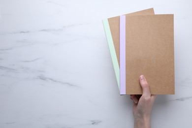 Photo of Woman with copybooks at white marble table, top view. Space for text