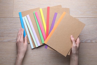 Photo of Woman with different copybooks at wooden table, top view