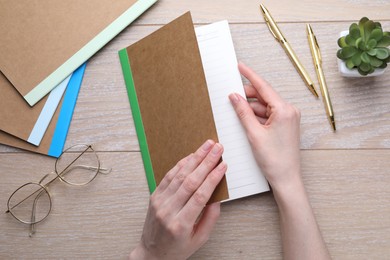 Photo of Woman with copybook and other stationery at wooden table, top view