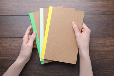 Photo of Woman with different copybooks at wooden table, top view