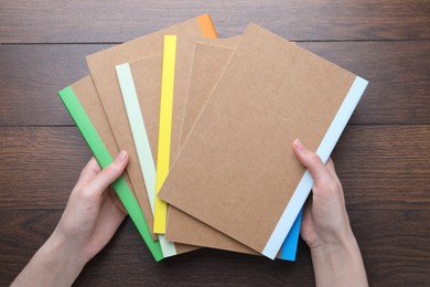 Photo of Woman with different copybooks at wooden table, top view