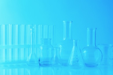 Photo of Different laboratory glassware on light blue background