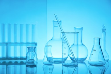 Photo of Laboratory glassware on mirror surface against light blue background