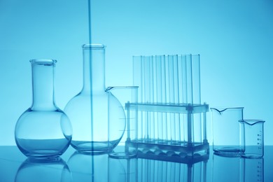 Photo of Laboratory glassware on mirror surface against light blue background