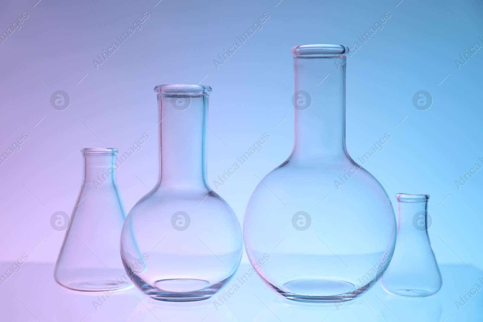 Photo of Empty flasks on color background. Laboratory glassware