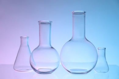 Photo of Empty flasks on color background. Laboratory glassware