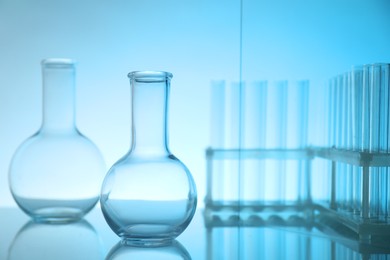 Laboratory glassware on mirror surface against light blue background