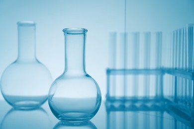 Laboratory glassware on mirror surface against light background