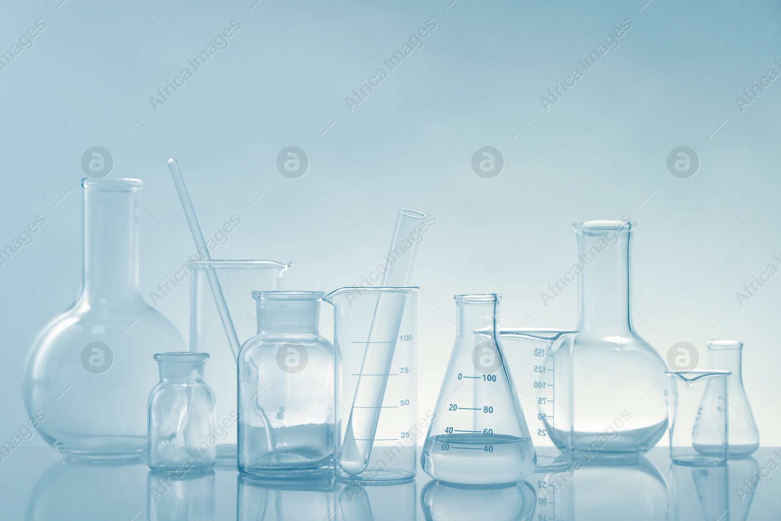 Photo of Laboratory glassware on mirror surface against light background