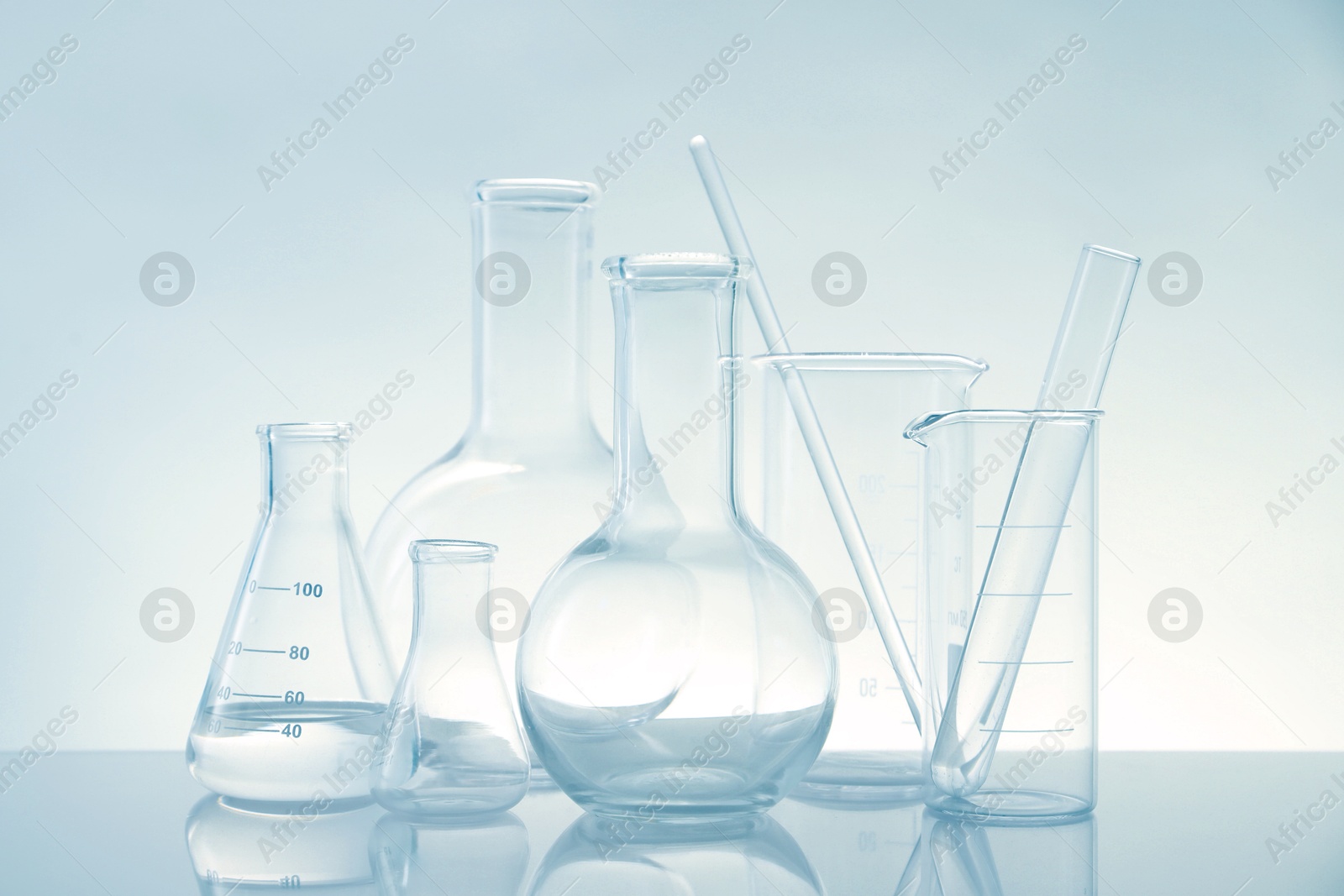 Photo of Laboratory glassware on mirror surface against light background