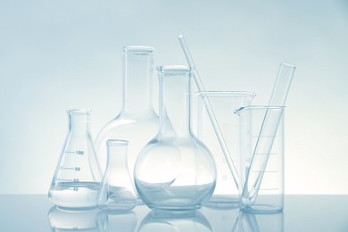 Photo of Laboratory glassware on mirror surface against light background