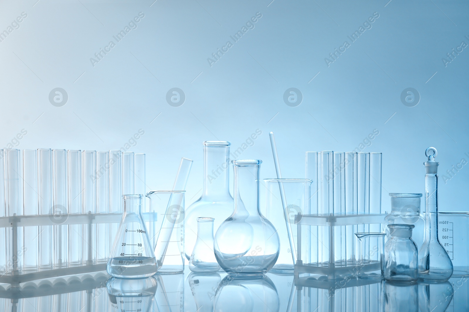 Photo of Laboratory glassware on mirror surface against light background