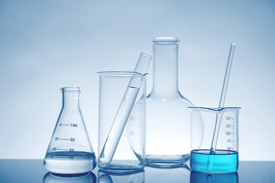 Photo of Laboratory glassware with liquid on mirror surface against light background