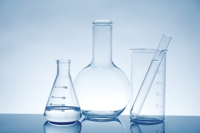 Photo of Laboratory glassware with liquid on mirror surface against light background