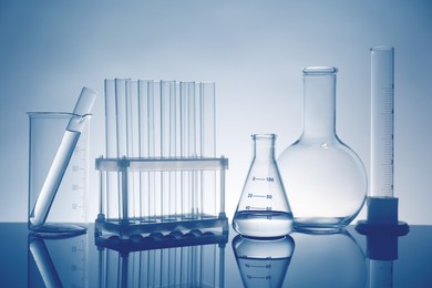 Photo of Laboratory glassware with liquid on mirror surface against light background