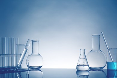 Photo of Laboratory glassware with liquid on mirror surface against light background