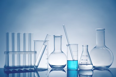 Laboratory glassware with liquid on mirror surface against light background