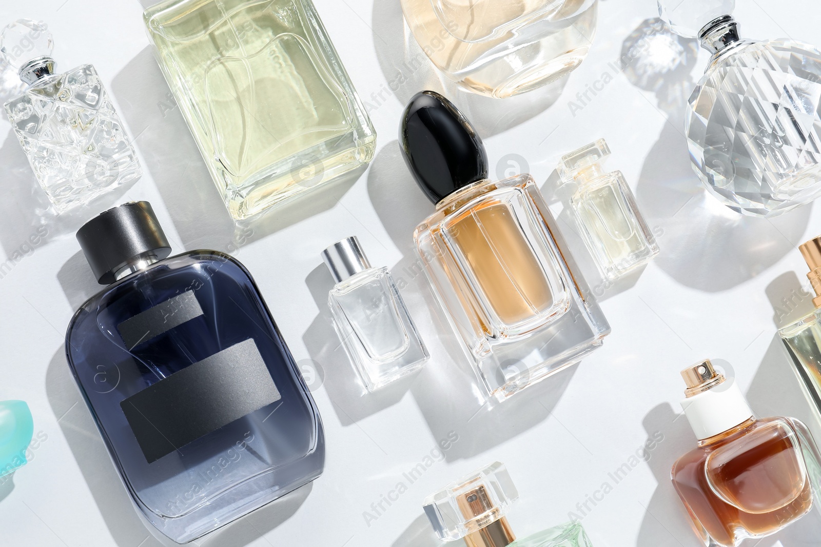 Bottles of various perfumes on light background, flat lay Photo of Bottles of various perfumes on light background, flat lay