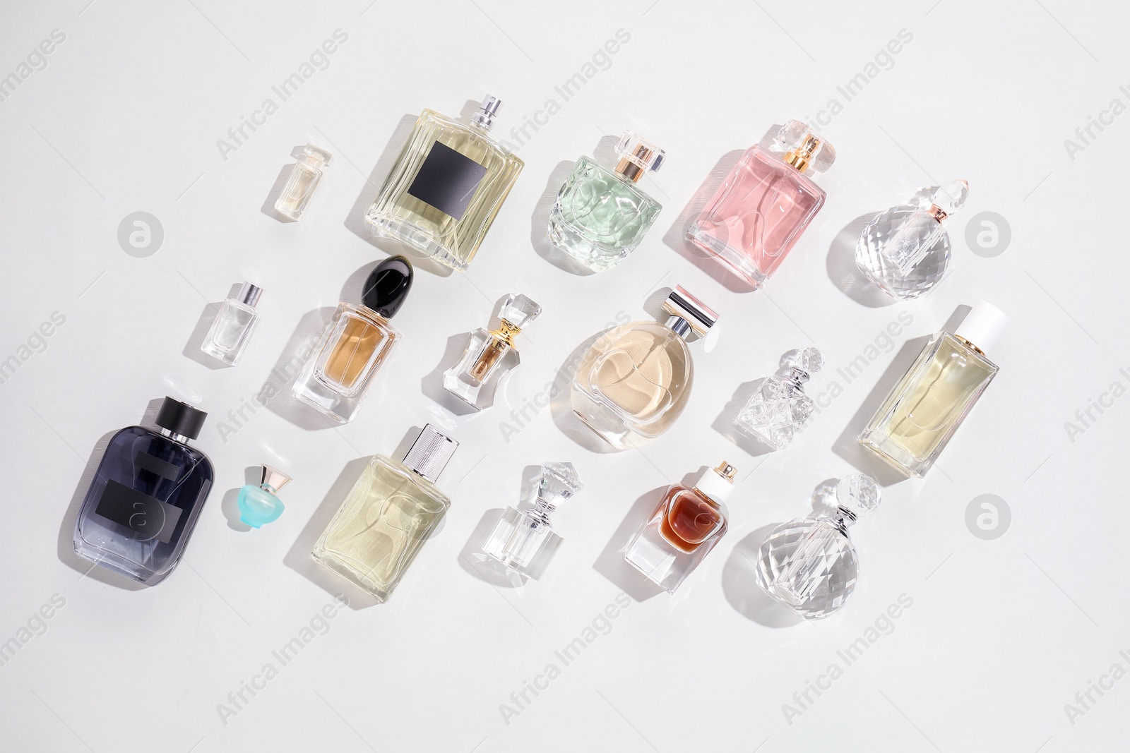 Bottles of various perfumes on light background, flat lay Photo of Bottles of various perfumes on light background, flat lay