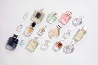 Photo of Bottles of various perfumes on light background, flat lay