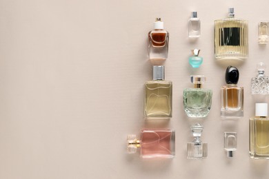 Photo of Bottles of various perfumes on beige background, flat lay. Space for text