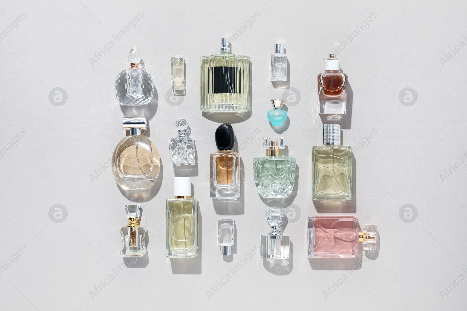 Bottles of various perfumes on beige background, flat lay Photo of Bottles of various perfumes on beige background, flat lay