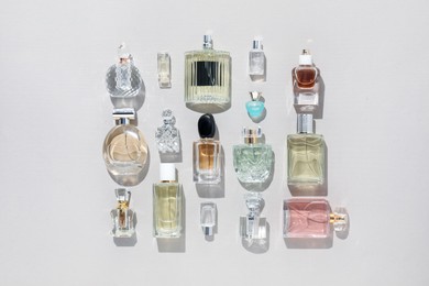 Photo of Bottles of various perfumes on beige background, flat lay