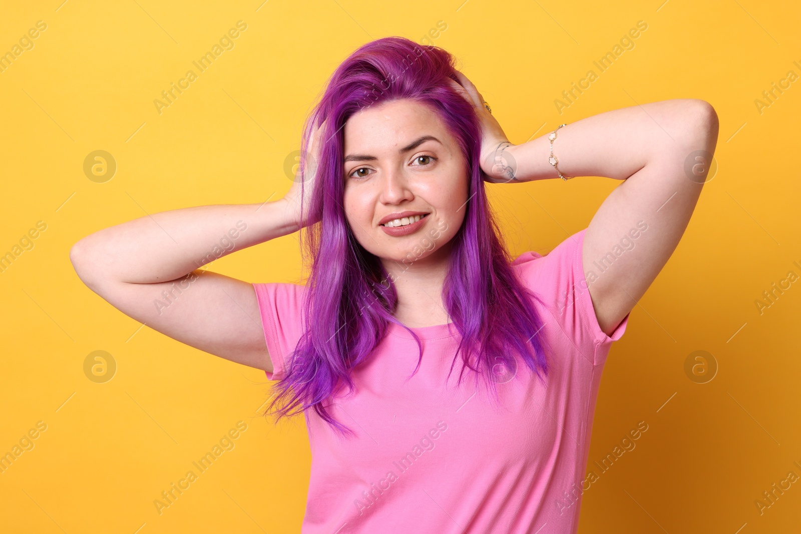 Beautiful woman with bright purple hair on yellow background Photo of Beautiful woman with bright purple hair on yellow background