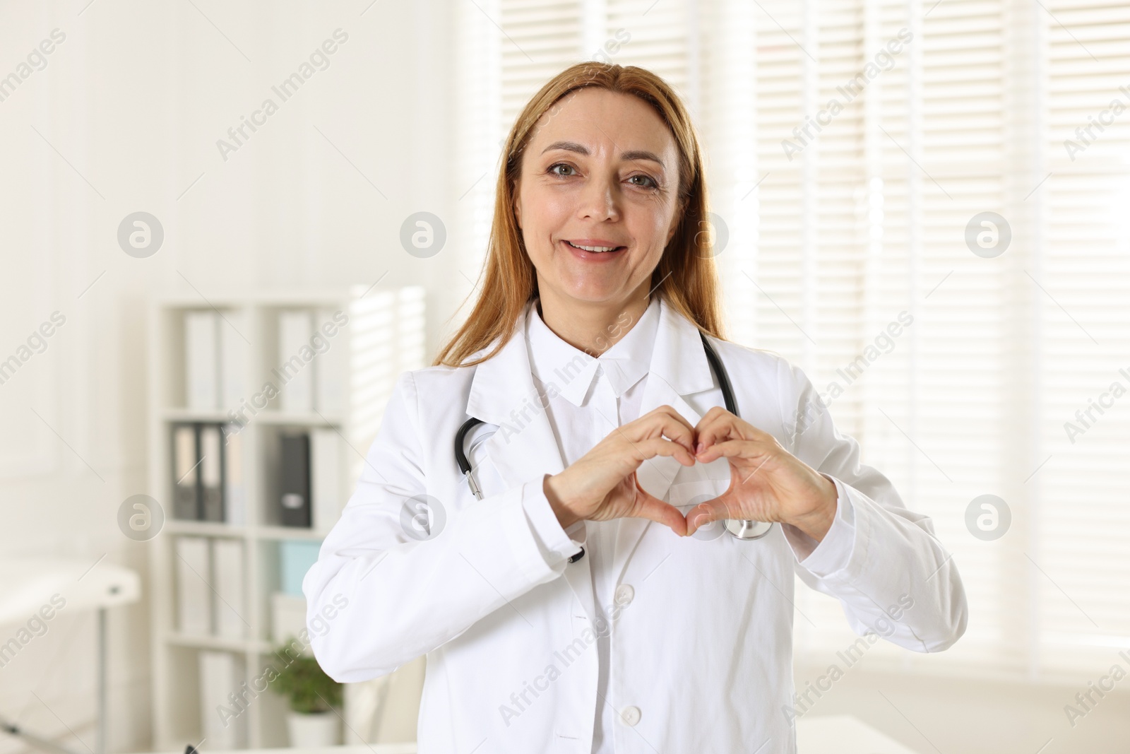 Photo of Cardiologist making heart with hands in hospital